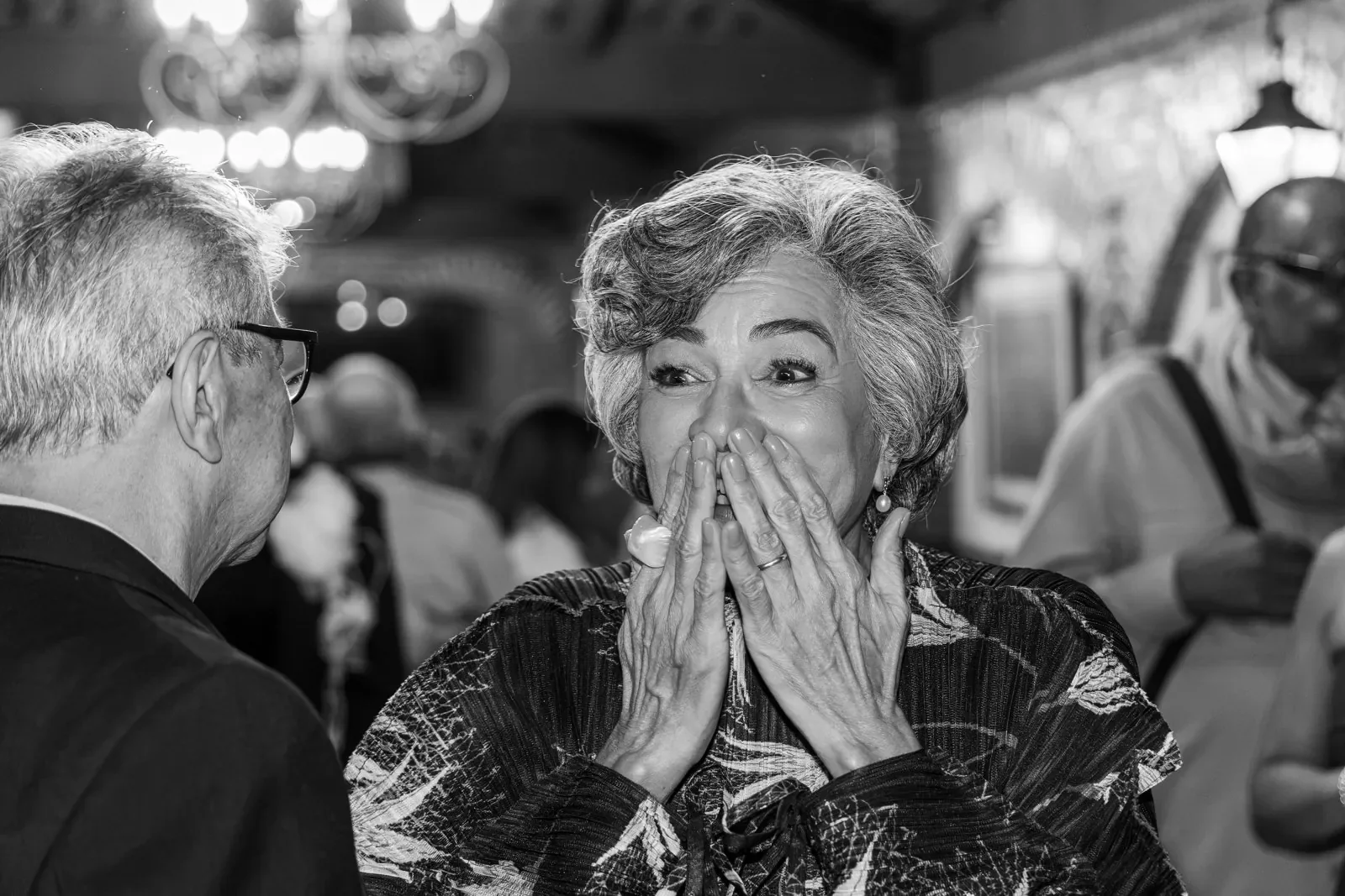Ete leva as mãos à boca, surpresa ao olhar para Ed, nas Bodas de Ouro, em preto e branco.